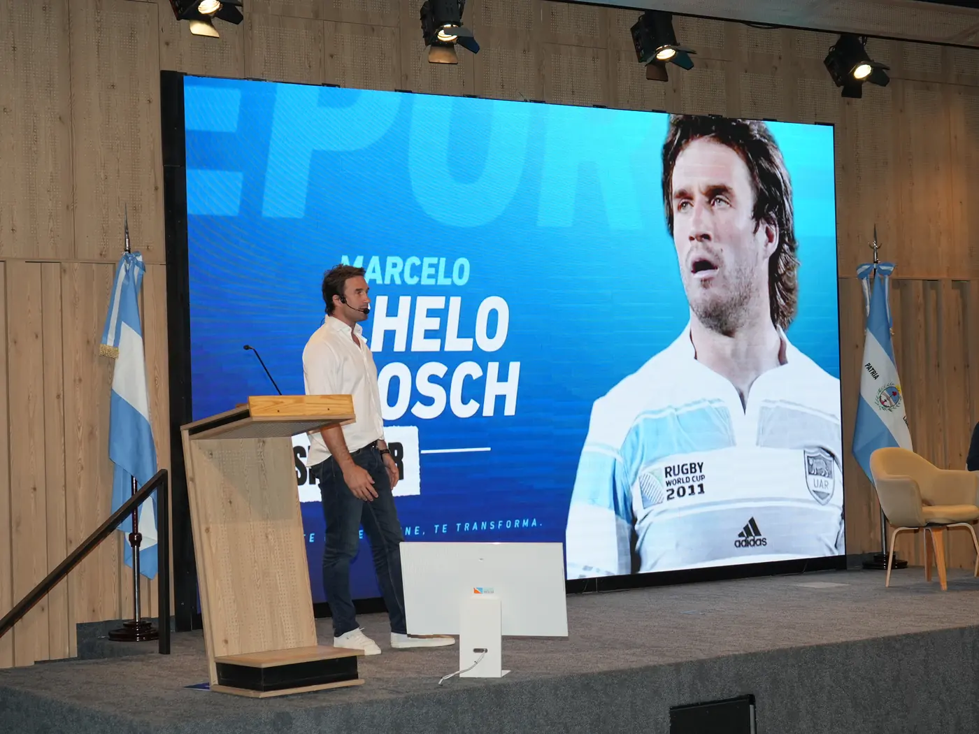 Marcelo Bosch habla en el atril, con su foto en la pantalla gigante